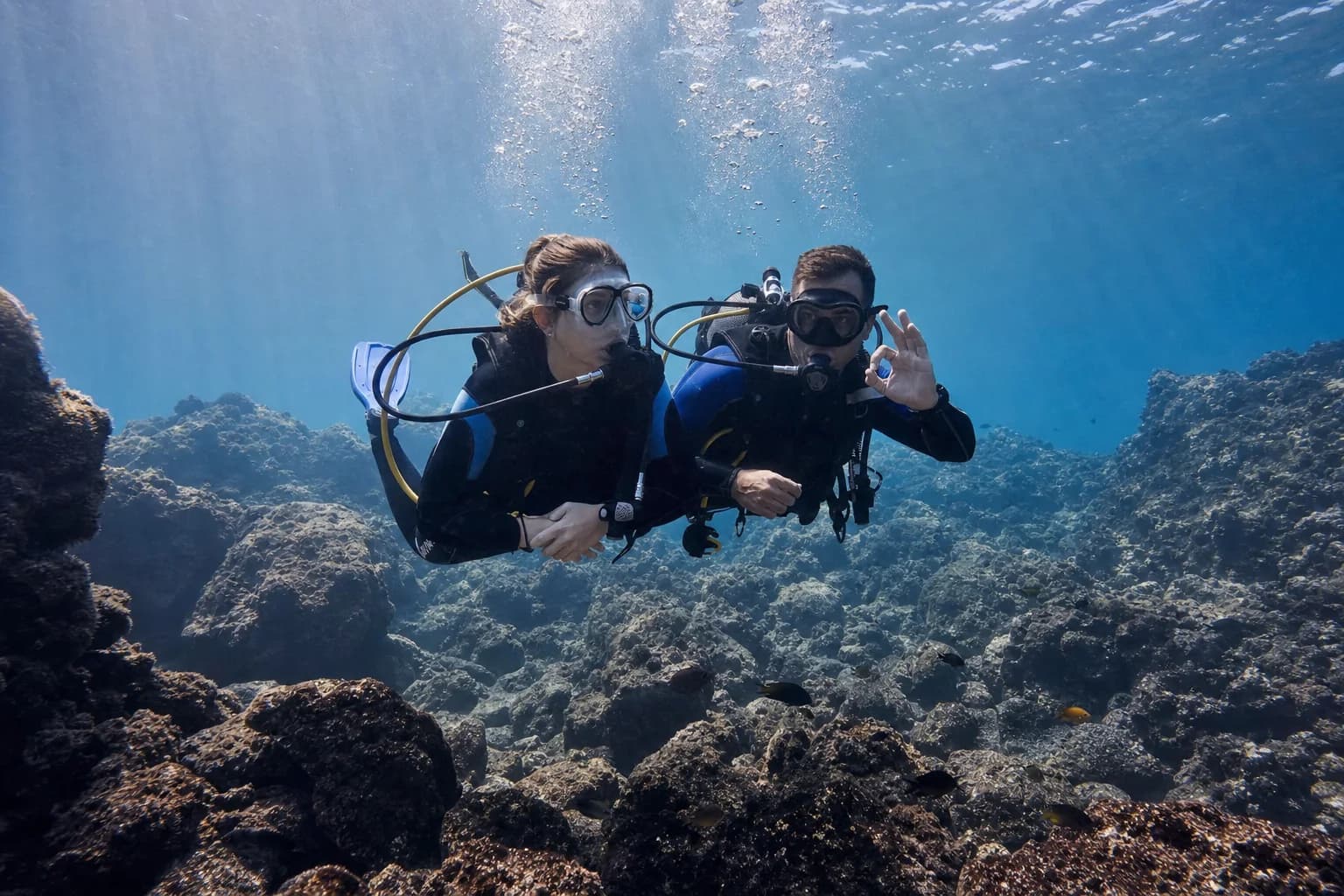 Beginner diver accompanied by an instructor above El Hierro's volcanic seabed